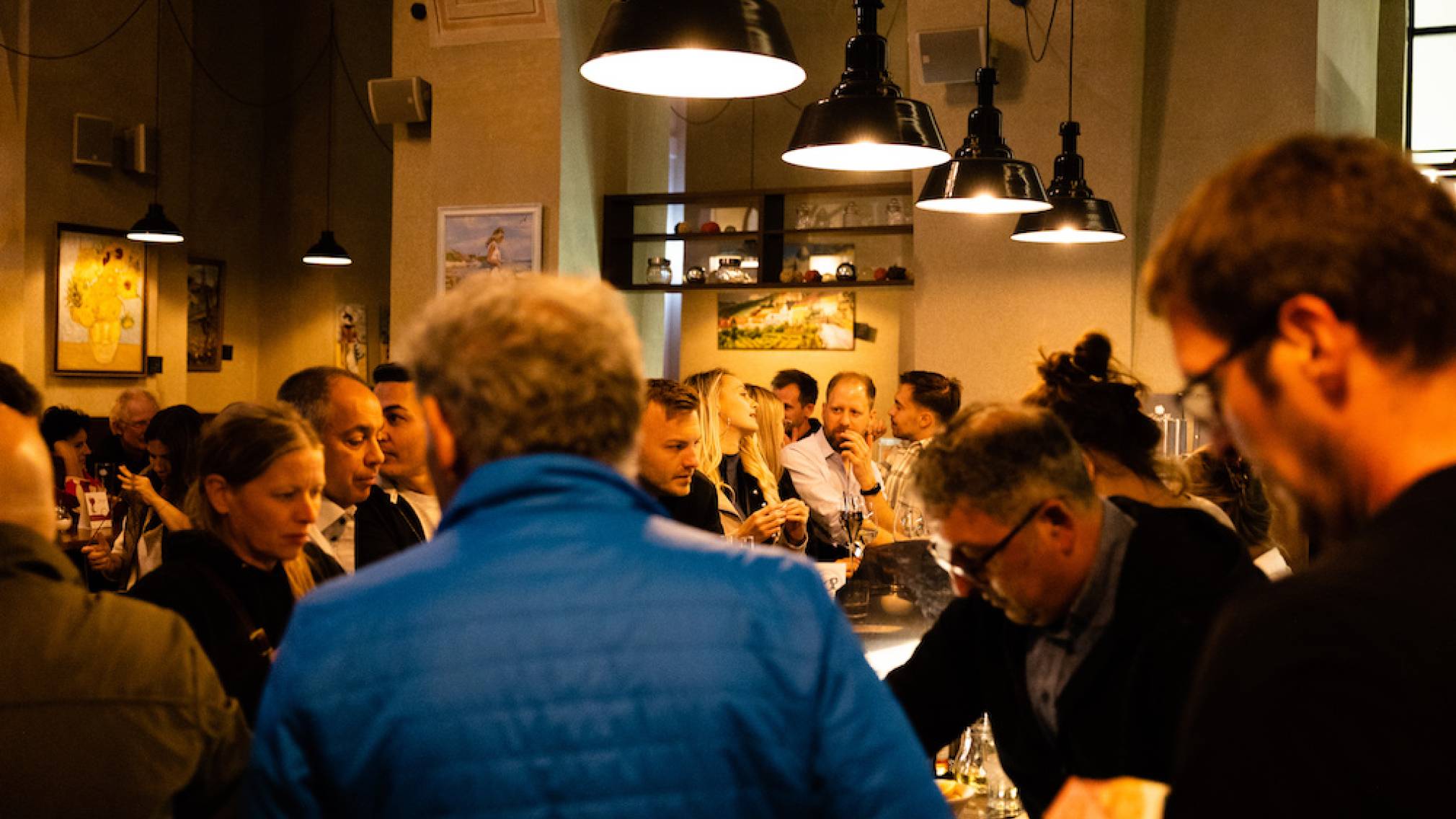 Zahlreiche Menschen stehen abends vor dem Weinlokal Vino in der schön beleuchteten St. Pöltner Innenstadt. Foto: Patrick Salfinger Fotografie